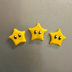 three yellow stars with black centers on a gray surface, one is facing the viewer