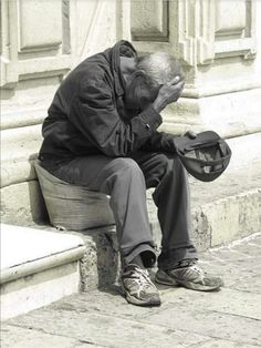 an old man sitting on the steps with his head in his hands