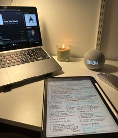 an open laptop computer sitting on top of a desk next to a cell phone and candle