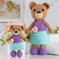 two crocheted teddy bears standing next to each other in front of a flower pot