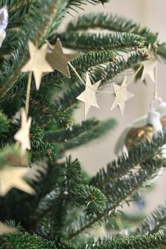 a christmas tree with ornaments hanging from it's branches and stars on the top