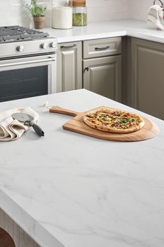 a pizza sitting on top of a wooden cutting board next to a stove and oven