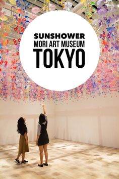 two women standing in front of a white circle with the words tokyo above it that says sunflower mohi at museum tokyo