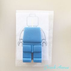 a blue lego figure sitting on top of a piece of paper