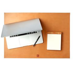 a laptop computer sitting on top of a desk next to a notepad and pen