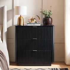 a bedroom with a bed, nightstand and plants on the side table in front of it