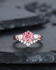 a pink and white diamond ring sitting on top of a rock