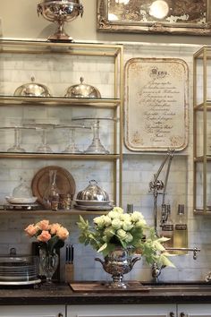 a kitchen counter topped with lots of dishes and vases filled with flowers on top of it