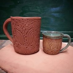 two mugs sitting on top of a table next to each other