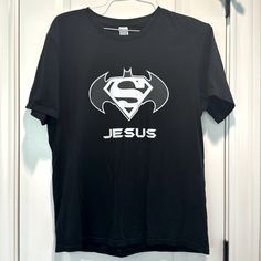 a black t - shirt with the word jesus printed on it and a superman logo