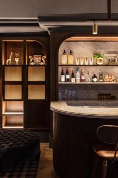 a bar with several bottles on the shelves and stools next to it in a room