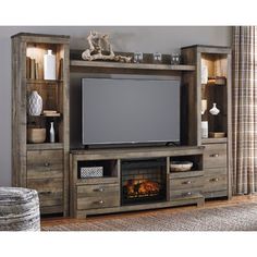 a living room with a fireplace and entertainment center that has a flat screen tv on it