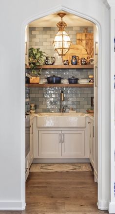 an open doorway leading to a kitchen with white cabinets and wooden flooring on the walls