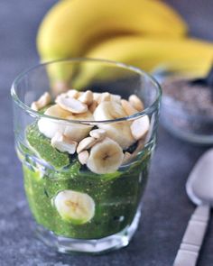 a banana and kiwi smoothie in a glass on a table next to bananas