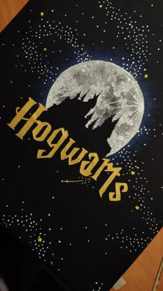 the hogwarts logo is painted on top of a black board with stars and moon in the background