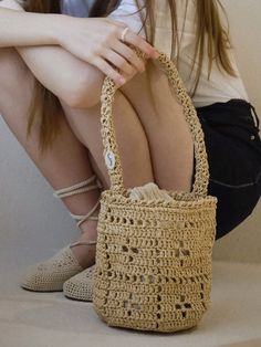 a woman sitting on the floor with her handbag in front of her face and legs crossed