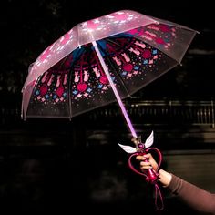 a woman holding an umbrella with pink and blue designs on it, in the dark