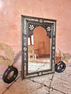 a mirror sitting on top of a floor next to a vase