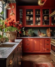 a kitchen filled with lots of red cabinets next to a stove top oven covered in pots and pans