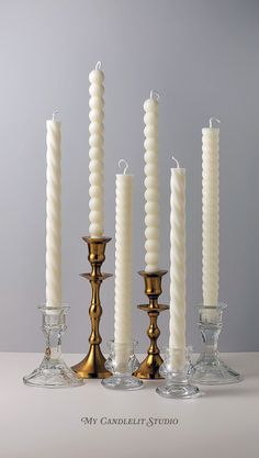 five candles are lined up next to each other in glass holders with gold rims