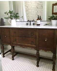 a bathroom with a double sink and wooden cabinet in the middle, surrounded by greenery