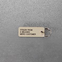 a metal keychain that says stolen from a beloved merci customer on it