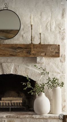 a fireplace with a mirror above it and vases on the mantle next to it