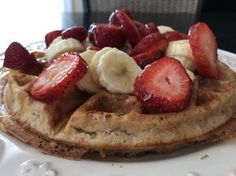 a waffle topped with sliced bananas and strawberries