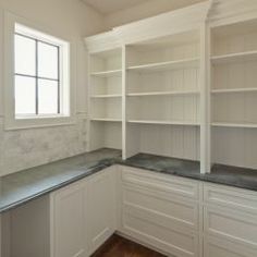 an empty kitchen with white cabinets and marble counter tops, along with hardwood floors in the middle