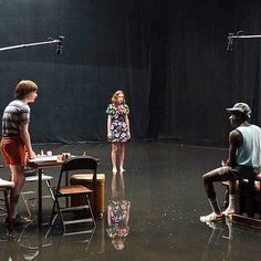 a group of people sitting around a table in the middle of a room with black walls