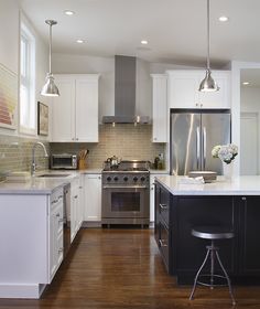 a kitchen with white cabinets, black island and stainless steel appliances in the center area