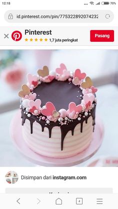 a pink and black cake with hearts on it's icing, sitting on top of a table