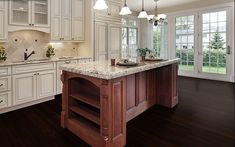 a large kitchen with white cabinets and marble counter tops, an island in the middle