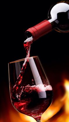 red wine being poured into a glass with flames in the background