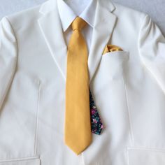 There is nothing like a versatile necktie that is solid on the front and a floral print tail to give your formal style an elegant and dapper touch. Simple and sophisticated make it the ideal neck tie to wear with most of your dress shirts and suits for any occasion.  Sold as a complete set:  necktie and pocket square Color:  Marigold Yellow Solid Front with Black Floral Print Tail (Back side)  Material:  100% Cotton Necktie:  approx. 2.75 inches wide and 58 inches long Pocket Square:  approx. 12 Classic Yellow Tie For Formal Occasions, Classic Gold Tie And Suit Accessories, Formal Yellow Tie, Yellow Suit And Tie Accessories For Black Tie Event, Dapper Gold Tie For Business, Dapper Suit And Tie Accessories For Wedding, Dapper Gold Accessories For Black Tie Suit, Classic Groom Ties, Classic Groom Suit And Tie Accessories