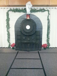 a black train engine sitting in front of a white brick fireplace with greenery around it