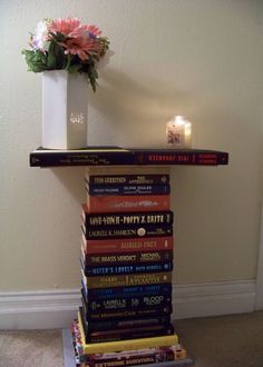 a stack of books sitting on top of a table next to a vase filled with flowers