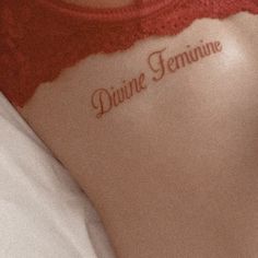 a close up of a person's back with the words divine feminine written on it