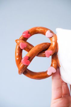 a hand holding a pretzel with hearts on it