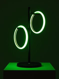 a green light that is on top of a black stand with two circular lights in the middle