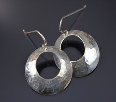 "Starting with 1\" sterling discs, a circle is punched out of the middle to create a donut.  The metal is hammered and then pressed into a dome shape.  Sterling ear wires are added.  Very light weight, simple, and pretty.  These earrings could go with anything--casual to formal." Artisan Hammered Round Hoop Earrings, Silver Hammered Circle Earrings, Silver Hammered Open Circle Earrings, Adjustable Hammered Circle Earrings, Hammered Silver Circle Earrings, Silver Hammered Round Earrings, Silver Hammered Round Hoop Earrings, Hammered Metal Hoop Earrings, Silver Hammered Hoop Earrings