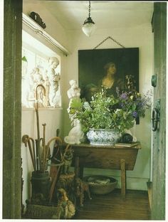 a painting is hanging on the wall next to a table with flowers and gardening utensils