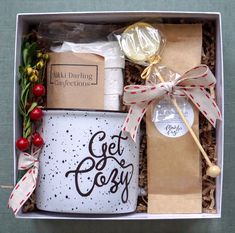 a gift box with coffee mug, marshmallows and other items in it