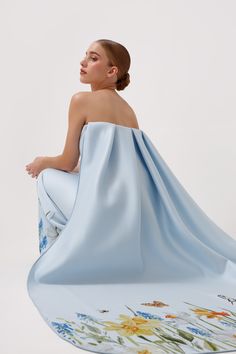 The Jasmine Gown in light blue is a strapless masterpiece that exudes sophistication and charm. Cut at the waist to flatter your figure, this gown features a unique garden/floral print on the hem for a whimsical touch. The standout feature is the removable statement cape, allowing you to customize your look for any special occasion. Perfect for making a lasting impression, the Jasmine Gown combines elegance with a dreamy, modern twist. Blue Jasmine, Unique Gardens, Short Rompers, Cape, Special Occasion, Floral Print, Light Blue, Floral Prints, Twist