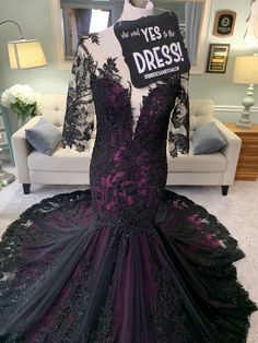 a black and purple dress on display in front of a white chair with a sign that says yes to the dress