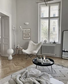 a living room filled with furniture and a large window next to a white rug on top of a hard wood floor