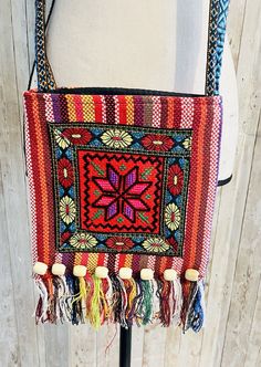 a multicolored bag with tassels hanging from it's side on a stand