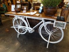 an old fashioned bicycle is on display in a store with potted plants behind it