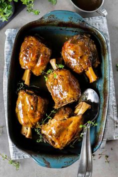 chicken thighs in a roasting pan with garnishes on the side and spoons