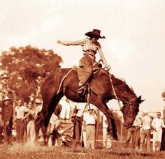 a man riding on the back of a brown horse next to a group of people